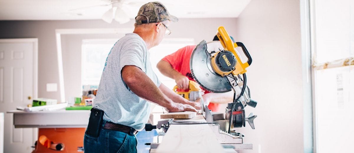 photo of two men with skill saw cutting lumber in home